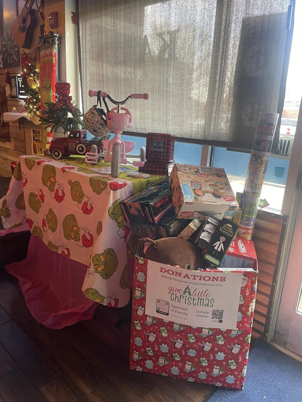A Give A Little Christmas donation box full of toys at a local restaurant